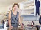 Mature saleswoman smiling while standing at the counter of a small store